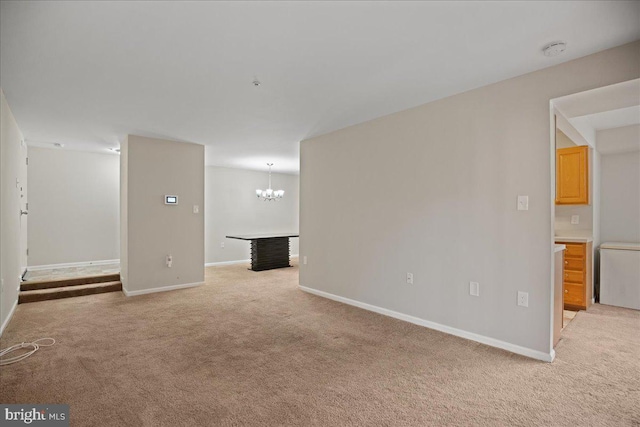 spare room featuring light colored carpet and an inviting chandelier