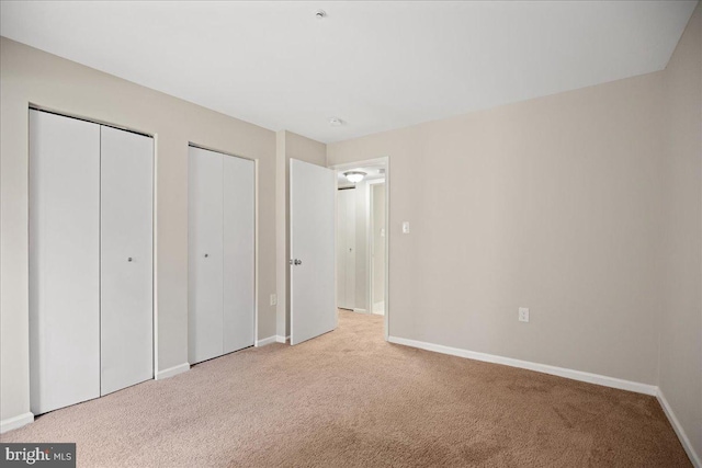 unfurnished bedroom with light carpet and two closets