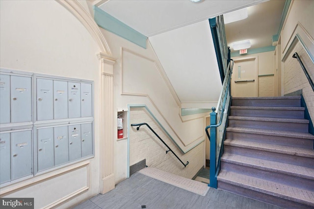 staircase with ornamental molding and a mail area