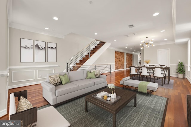 living room with ornamental molding, a chandelier, and hardwood / wood-style flooring