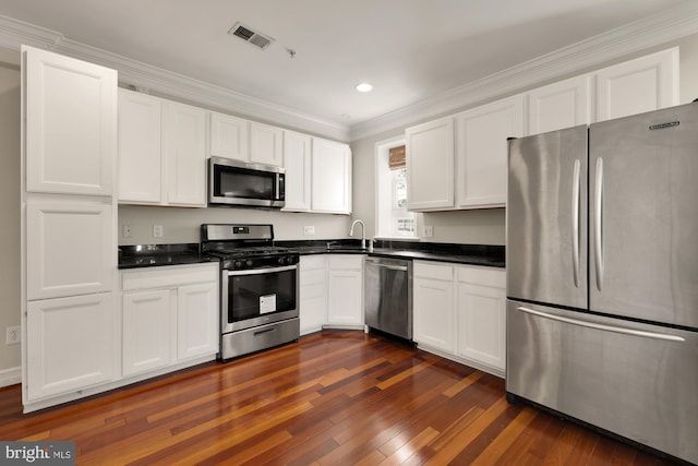 kitchen featuring white cabinets, ornamental molding, dark wood-type flooring, sink, and stainless steel appliances