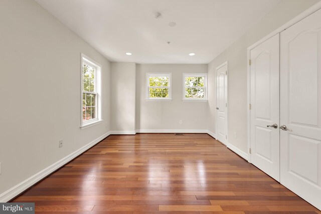 unfurnished bedroom with hardwood / wood-style flooring and multiple windows