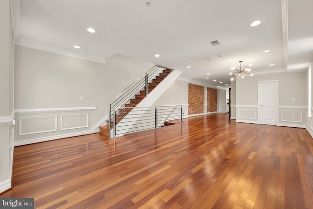 spare room with an inviting chandelier, ornamental molding, and wood-type flooring