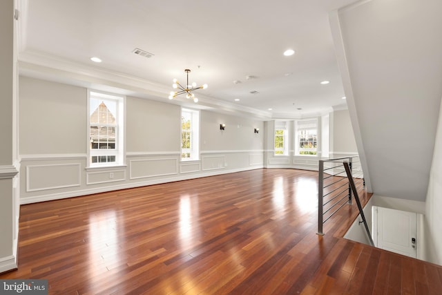 unfurnished living room with wood-type flooring, ornamental molding, and an inviting chandelier