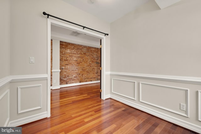 spare room featuring light hardwood / wood-style flooring and brick wall