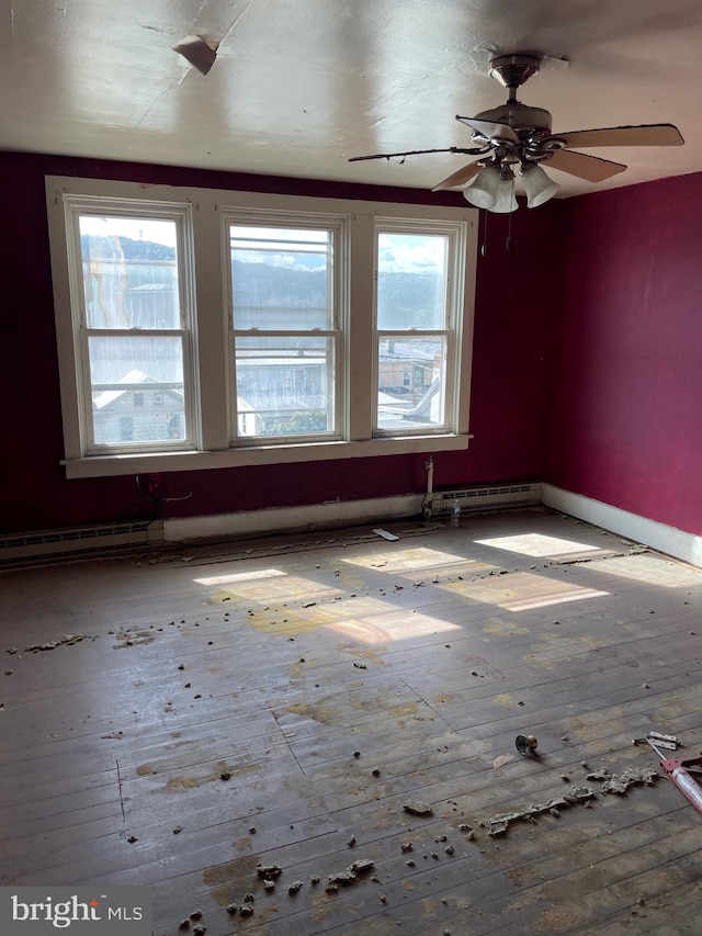 spare room featuring ceiling fan, a baseboard radiator, hardwood / wood-style floors, and a healthy amount of sunlight