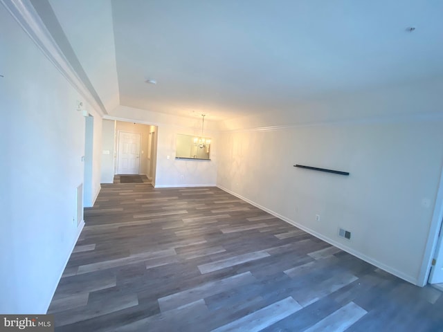 unfurnished room featuring a chandelier and dark wood-type flooring