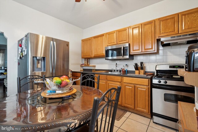 1337 S 54th St, Philadelphia, PA 19143 - kitchen with light tile patterned flooring, under cabinet range hood, decorative backsplash, stainless steel appliances, and a sink