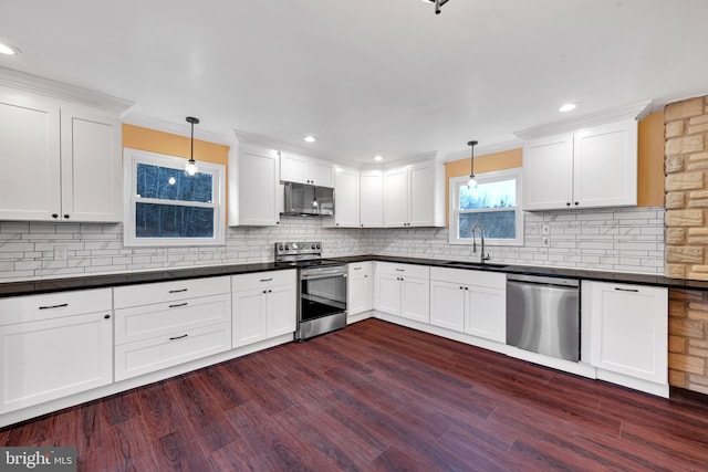 kitchen with sink, dark wood-type flooring, decorative light fixtures, and appliances with stainless steel finishes