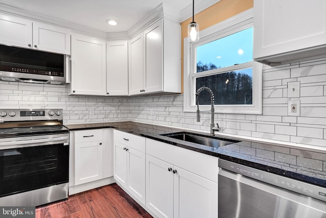 kitchen featuring dark wood-type flooring, white cabinets, sink, hanging light fixtures, and stainless steel appliances