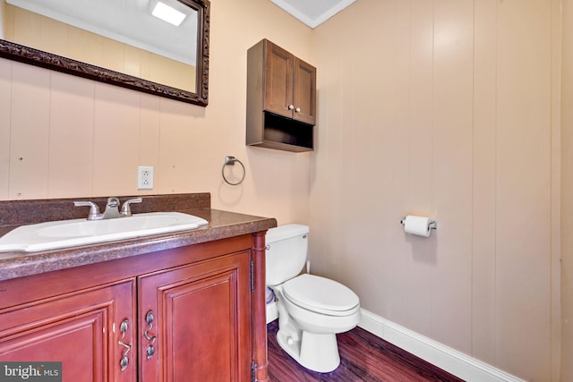 bathroom featuring toilet, vanity, ornamental molding, and hardwood / wood-style flooring