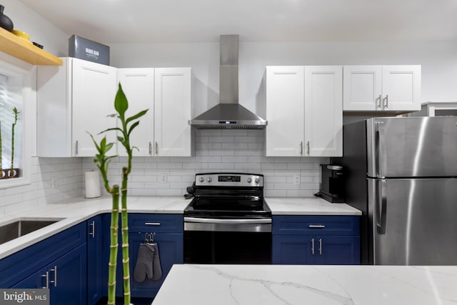 kitchen with blue cabinetry, wall chimney range hood, backsplash, and appliances with stainless steel finishes