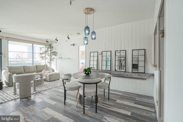 dining area featuring dark wood-type flooring and wood walls