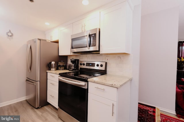 kitchen featuring white cabinetry, light stone countertops, light hardwood / wood-style flooring, and stainless steel appliances