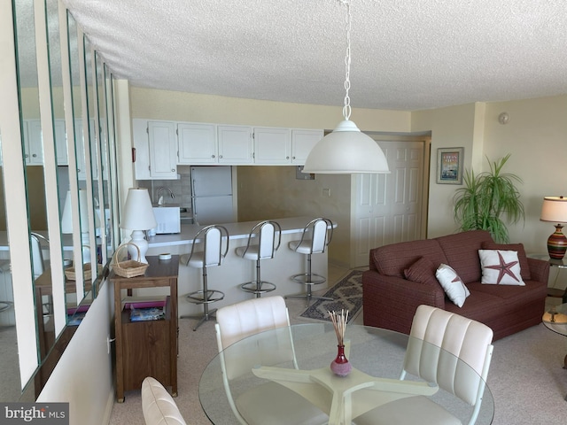 carpeted dining area with a textured ceiling