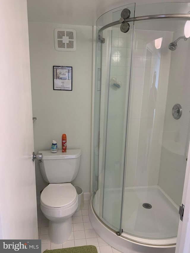 bathroom featuring a shower with door, toilet, and tile patterned floors