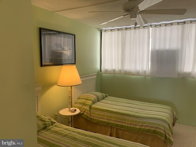 carpeted bedroom featuring ceiling fan and a textured ceiling