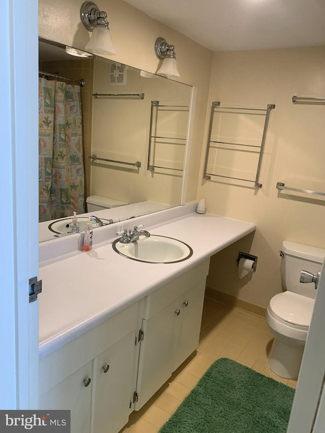 bathroom with toilet, vanity, and tile patterned floors