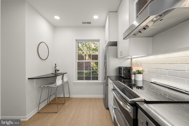 kitchen featuring tasteful backsplash, ventilation hood, stainless steel range with electric cooktop, light hardwood / wood-style flooring, and white cabinetry