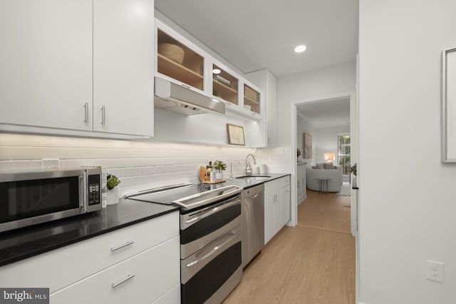 kitchen featuring sink, tasteful backsplash, white cabinetry, appliances with stainless steel finishes, and light wood-type flooring