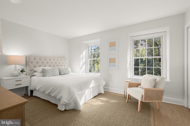 bedroom with multiple windows and light hardwood / wood-style floors