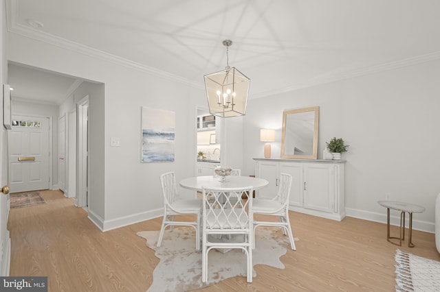 dining space featuring an inviting chandelier, ornamental molding, and light hardwood / wood-style flooring