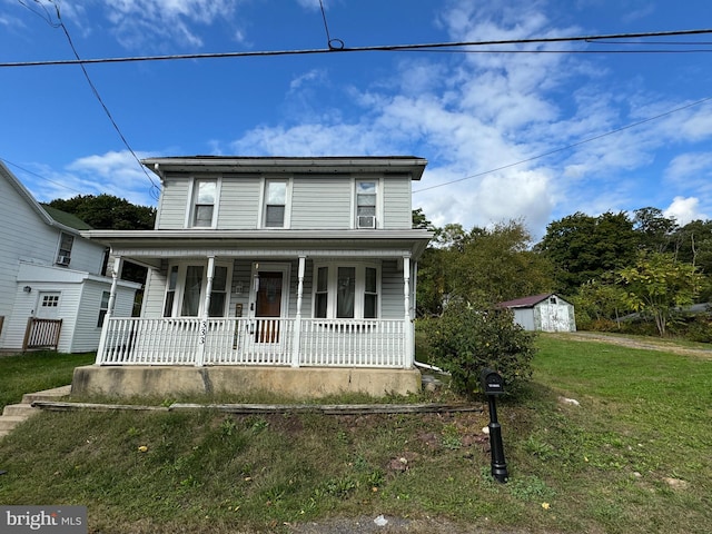 view of front facade featuring a front yard, a storage shed, and covered porch