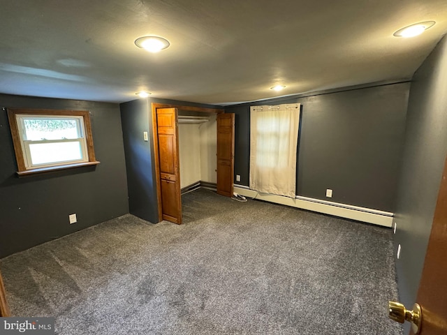 unfurnished bedroom with dark carpet and a baseboard heating unit