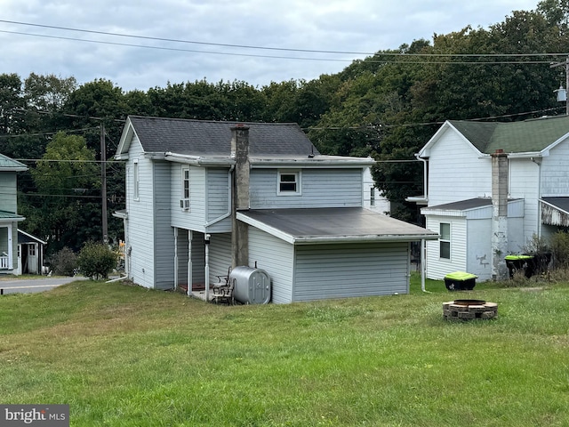 rear view of house with a fire pit and a lawn