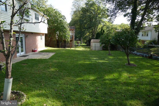 view of yard featuring a storage unit, a patio area, and french doors