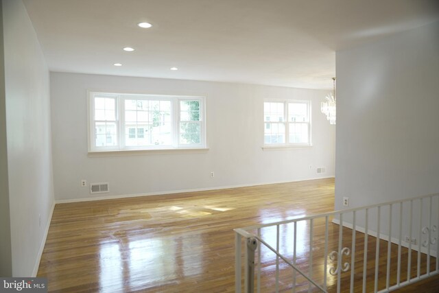 empty room with an inviting chandelier and light hardwood / wood-style flooring