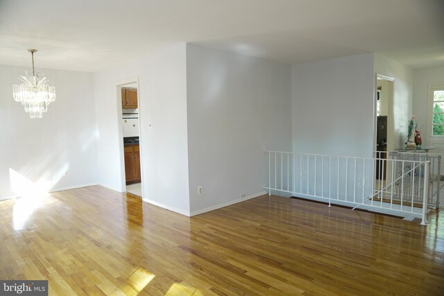 empty room featuring hardwood / wood-style flooring and an inviting chandelier