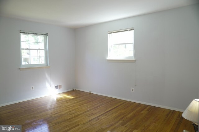 unfurnished room with dark wood-type flooring