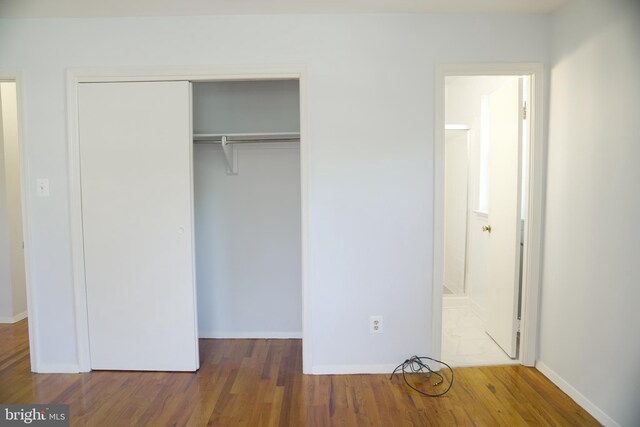 unfurnished bedroom with a closet, connected bathroom, and dark hardwood / wood-style flooring