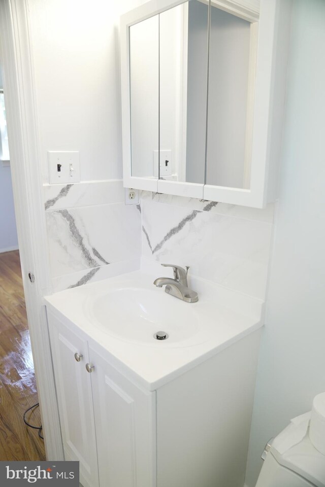 bathroom with vanity, toilet, hardwood / wood-style flooring, and backsplash