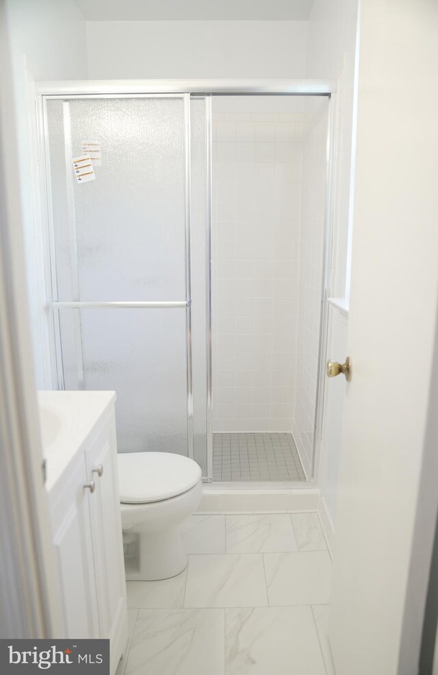 bathroom featuring vanity, an enclosed shower, and toilet