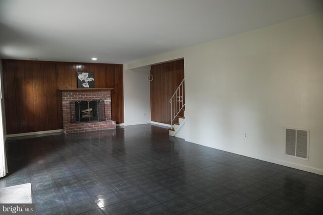 unfurnished living room with wood walls and a fireplace