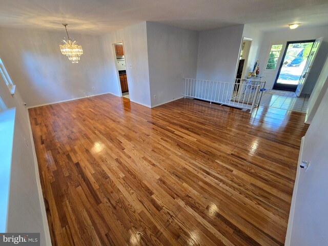 spare room featuring a notable chandelier and hardwood / wood-style flooring