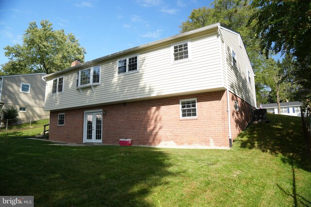 rear view of house featuring french doors and a lawn