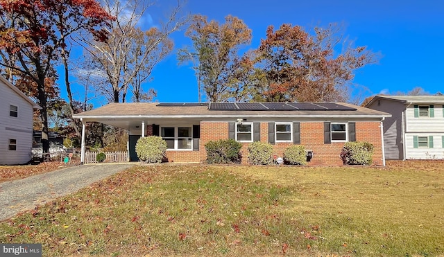 view of front facade with solar panels, a front yard, and a carport