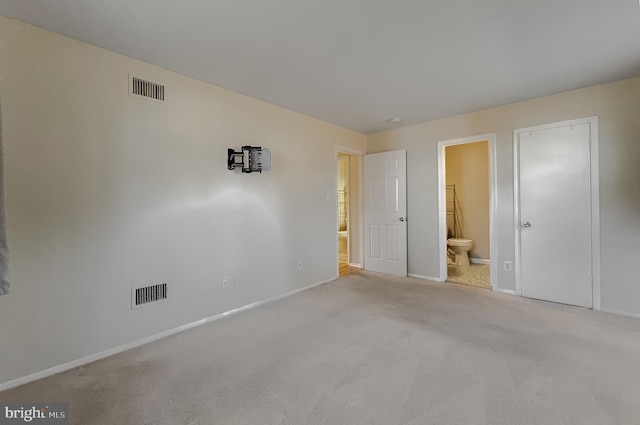 unfurnished bedroom featuring ensuite bathroom and light colored carpet