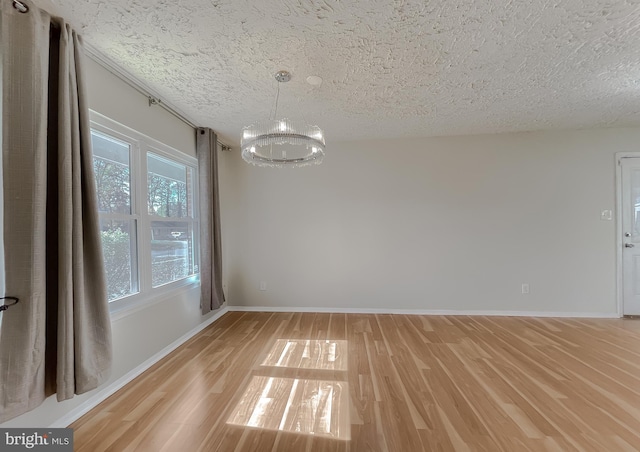 unfurnished dining area with a chandelier, a textured ceiling, and light hardwood / wood-style flooring