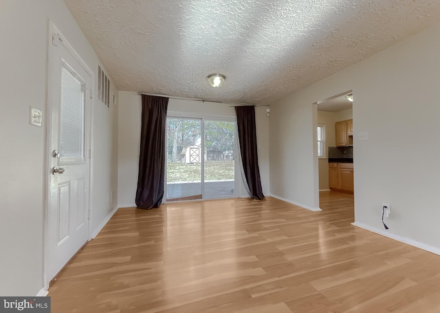 unfurnished room featuring light hardwood / wood-style floors and a textured ceiling