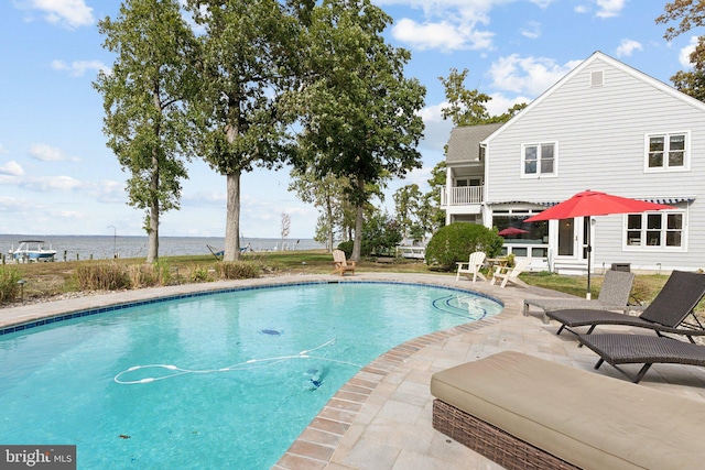 view of swimming pool featuring a water view and a patio