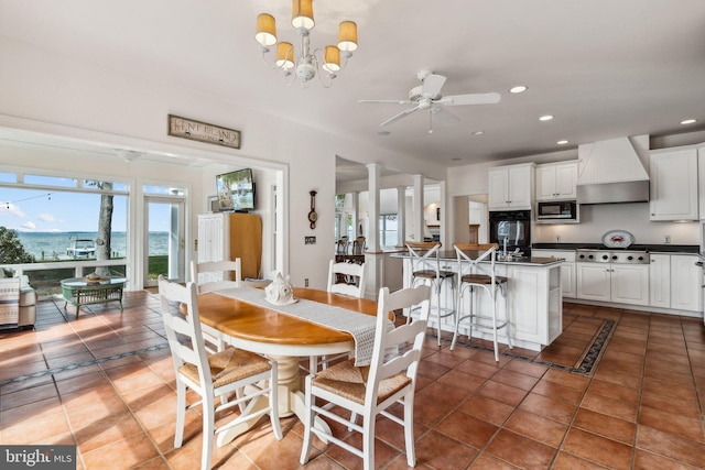 dining space with ceiling fan with notable chandelier and dark tile patterned floors