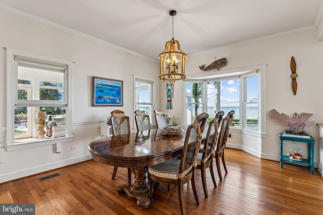 dining area featuring ornamental molding, an inviting chandelier, and wood-type flooring