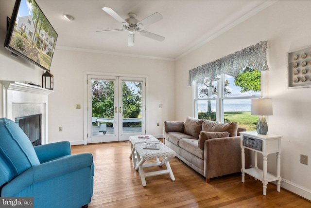 living room with ceiling fan, light hardwood / wood-style flooring, a fireplace, and crown molding