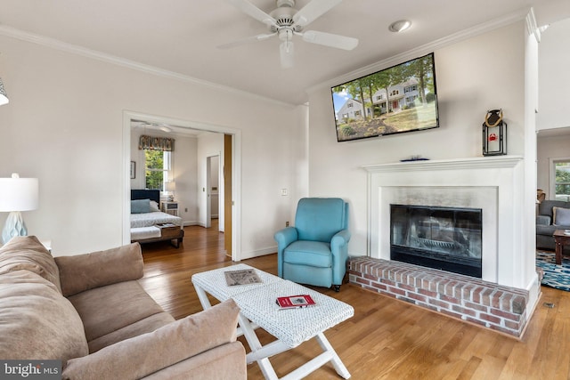 living room featuring a brick fireplace, crown molding, ceiling fan, and hardwood / wood-style floors