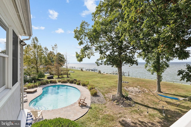 view of pool with a water view, a patio, and a yard