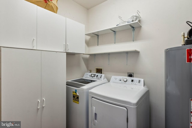 washroom featuring gas water heater, cabinets, and washer and clothes dryer